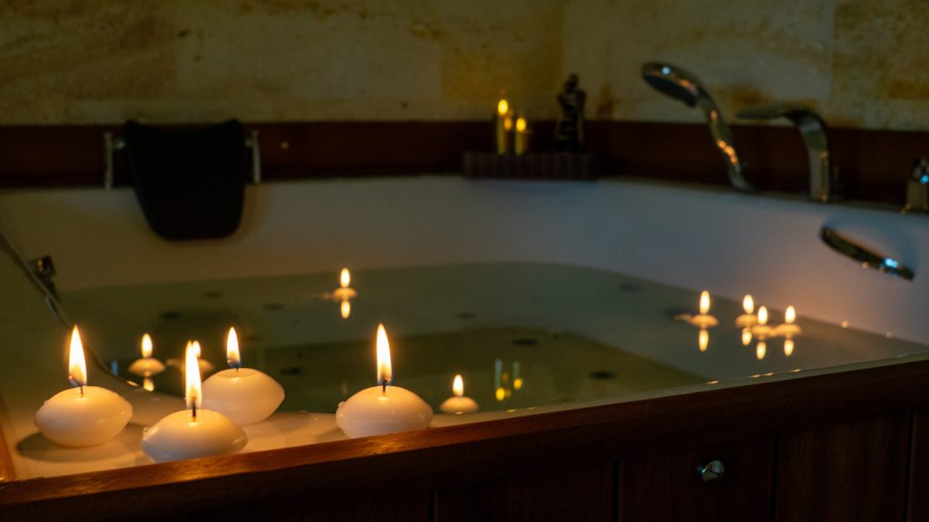Romantik balayı konsepti – şampanya kadehleri, kırmızı gül yaprakları, mum ışığı ve yüzük kutusu